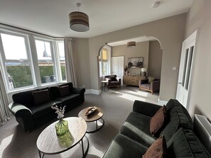 A modern living room with a sofa set, a coffee table, and a dining area with a cabinet and chairs. - Abbotsford (Kelso)