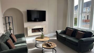 A living room with a flat-screen TV, a fireplace, a sofa, and a coffee table.