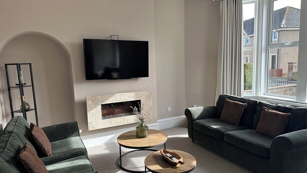 Ein Wohnzimmer mit Fernseher, Kamin, zwei Sofas und einem Fenster.