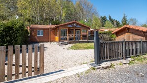 Une cabane en bois avec une allée gravillonnée, une clôture en bois et un ciel dégagé.