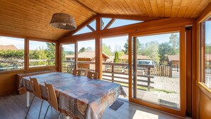 Une pièce aux murs lambrissés, avec une table et des chaises, de grandes fenêtres et une vue sur l’extérieur.