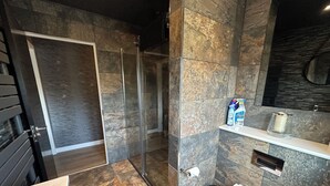 Uma casa de banho moderna com chuveiro, sanita e lavatório.