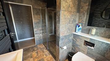 A modern bathroom with a shower, toilet, and sink.