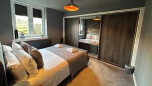 Um quarto com uma cama, mesas de cabeceira, uma janela e um guarda-roupa.