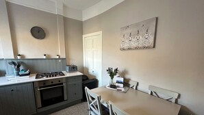 A compact kitchen with a gas stove, a toaster, and a clock on the wall. - The Tweed (Melrose)