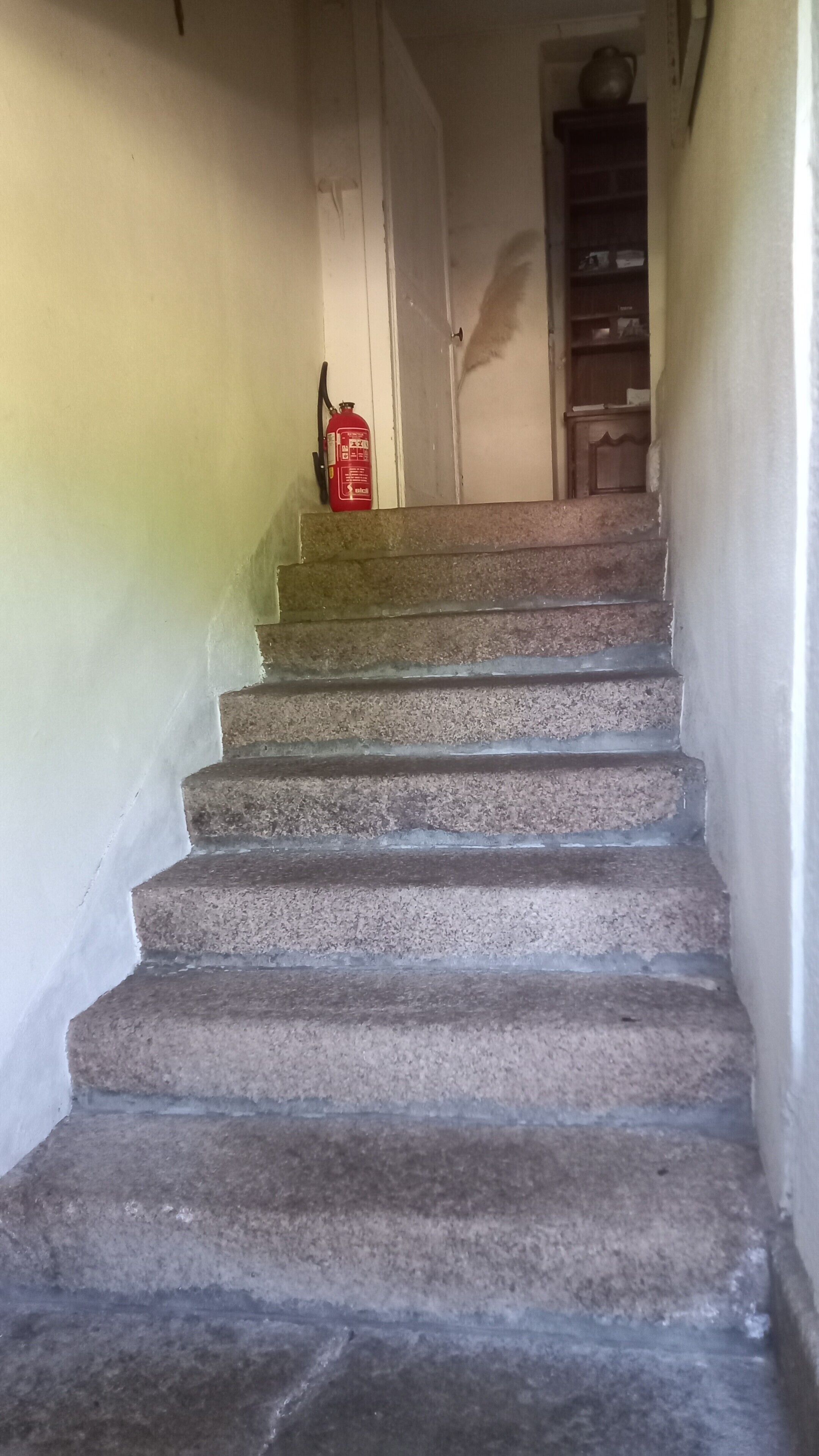 A staircase with a fire extinguisher on the landing.