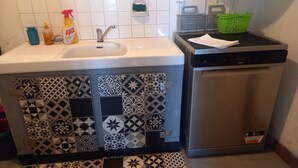 Ett kök med diskho, diskmaskin och ett mönstrat stänkskydd.