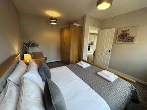 Une chambre d’hôtel comprenant un lit, une table de chevet, une lampe, une armoire et une porte donnant accès à une salle de bain.