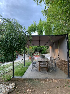 Une terrasse extérieure agrémentée d’une pergola, d’une table à manger avec des chaises et de plantes en pot.