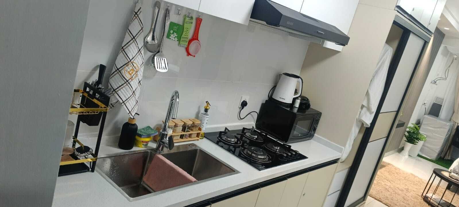 Una cocina compacta con estufa a gas, cafetera y lavamanos.