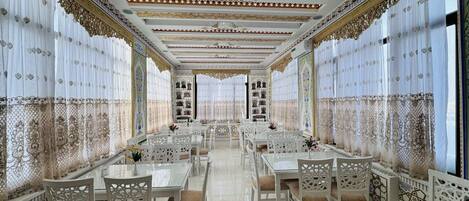 A spacious dining area with ornate white furniture and intricate ceiling designs.