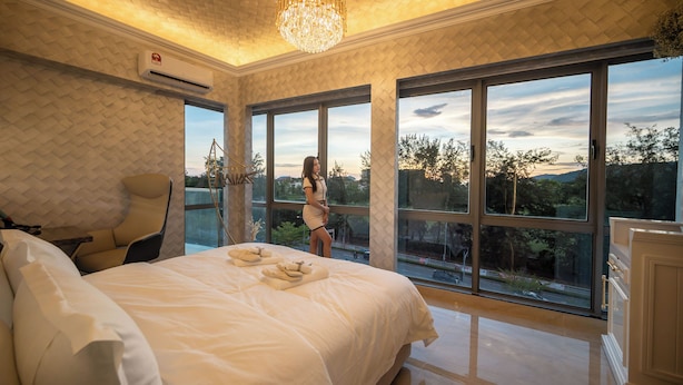 Un dormitorio amplio con una cama grande, una zona de estar y vistas al exterior a través de amplios ventanales.