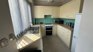 A compact kitchen with a sink, stove, microwave, and a refrigerator. - Pergola (Melrose)