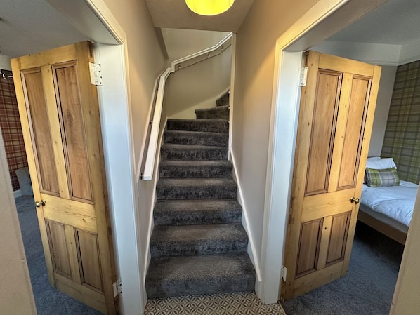 A staircase with carpeted steps leading to a bedroom with a bed and a window. - Pergola (Melrose)