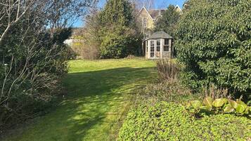 A garden with a gazebo, a lawn, and various trees.