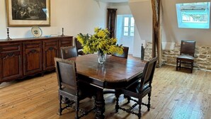 A dining room with a wooden table, chairs, a chandelier, a painting, and a window. - Château de la Pervenchère - Gîte des Cavaliers (Casson)