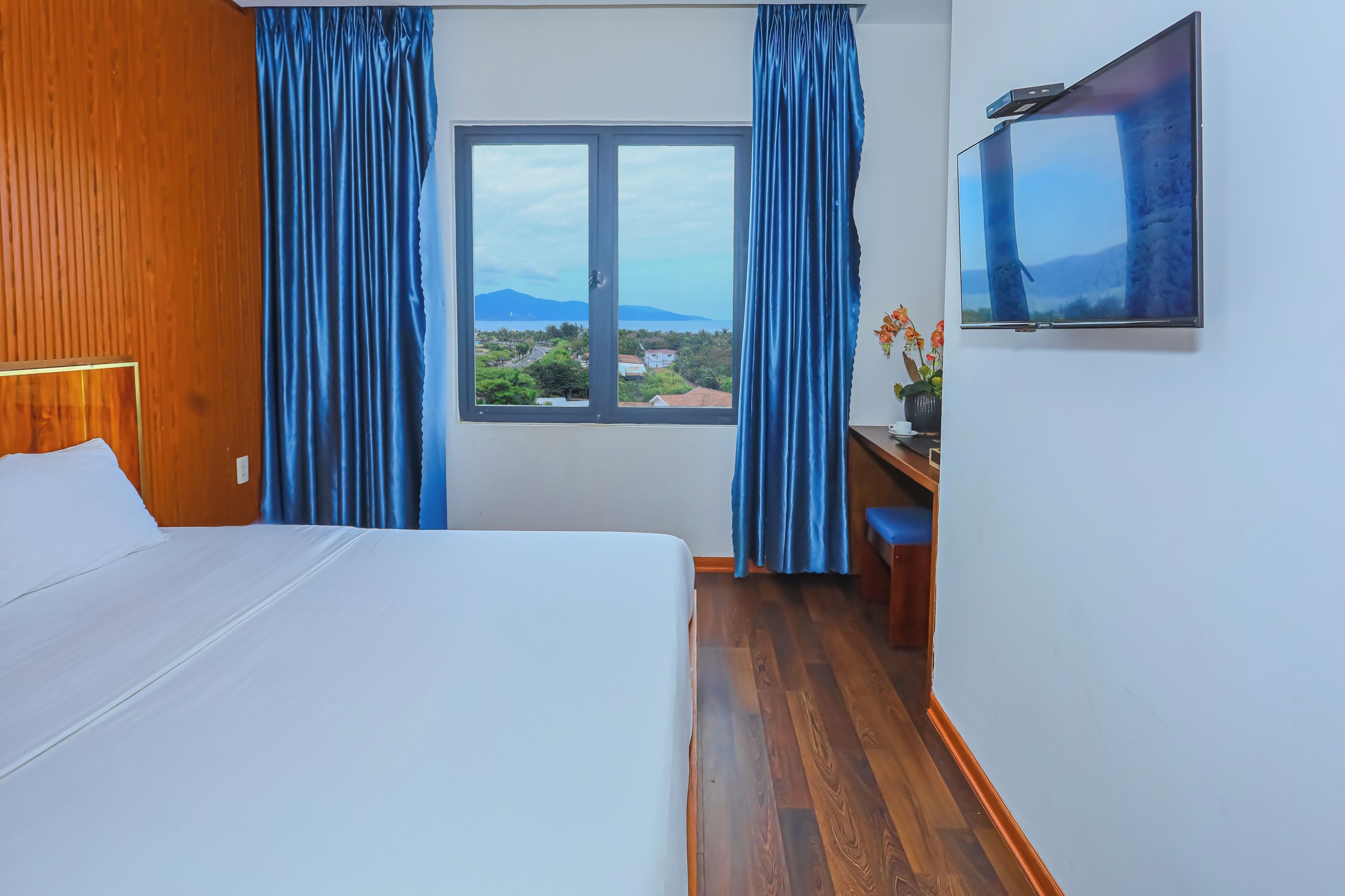 Ein Hotelzimmer mit Bett, Schreibtisch, Fernseher und einem Fenster mit Vorhängen.