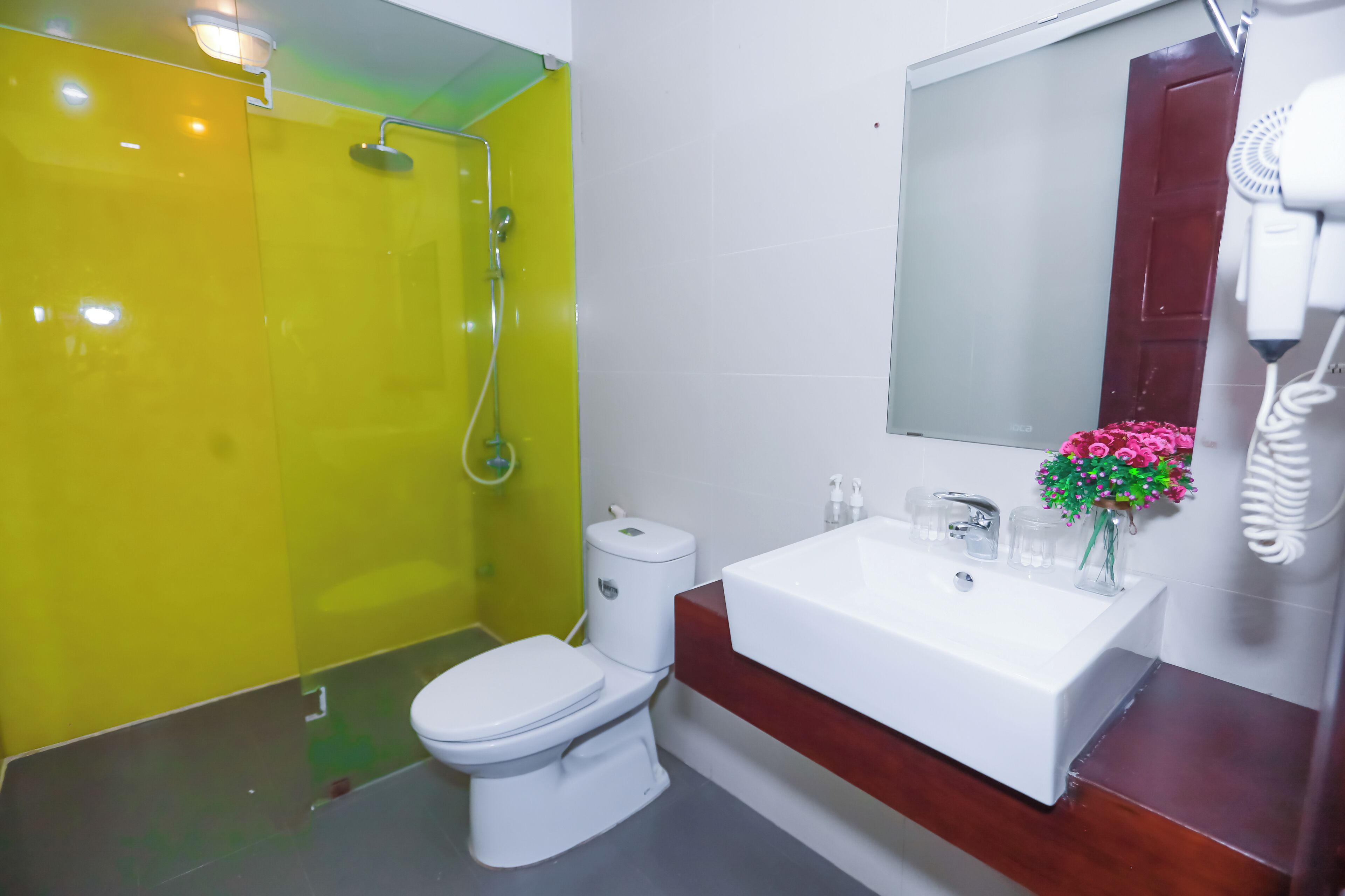 Un baño con ducha amarilla, inodoro blanco y lavamanos con espejo.