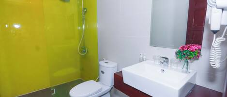 Un baño con ducha amarilla, inodoro blanco y lavamanos con espejo.