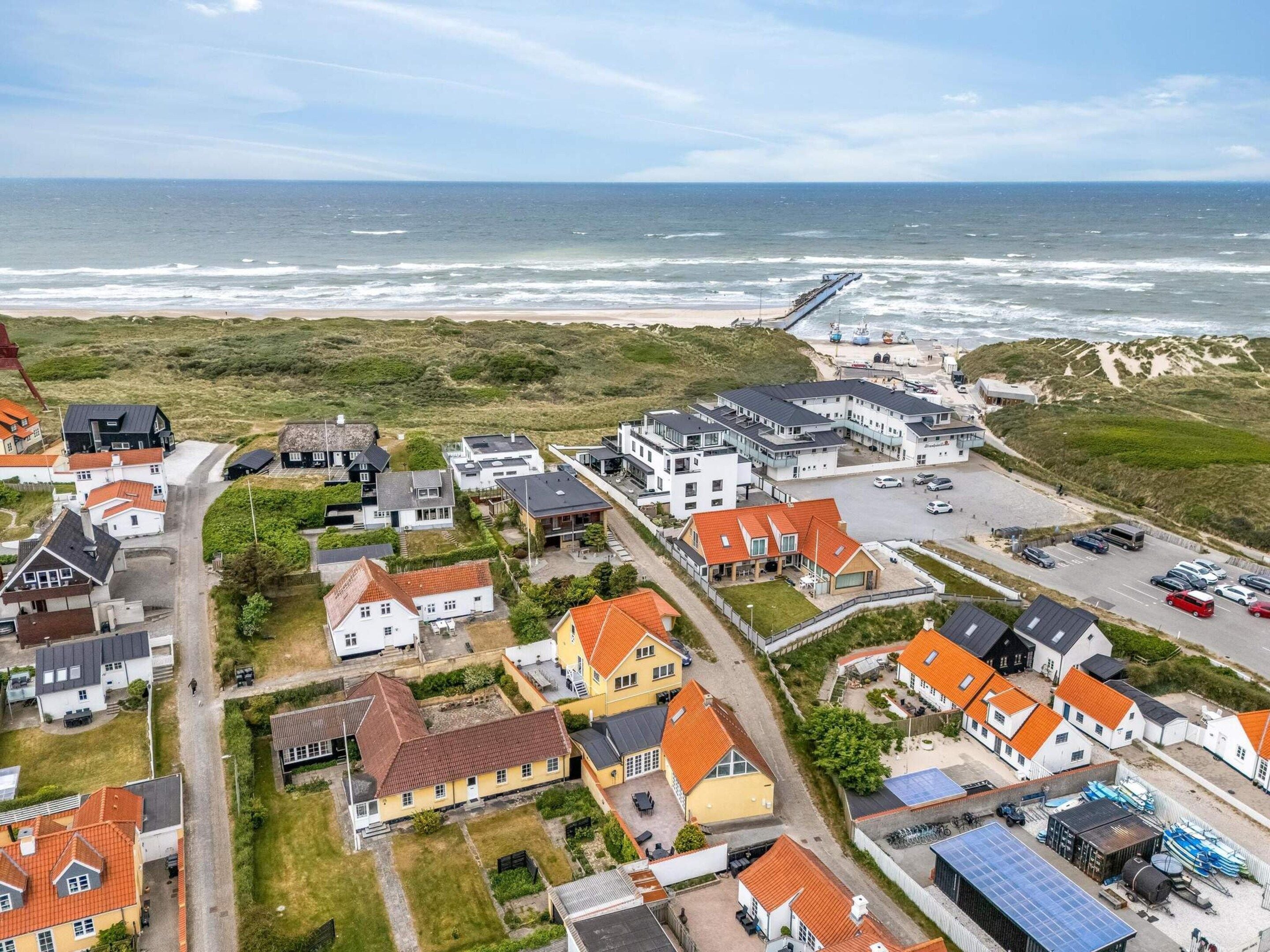 A coastal residential area with houses, a beach, and a pier.