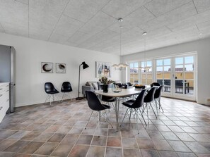 A spacious dining area with a large table and chairs, a floor lamp, and artwork on the walls. - 4 Star Holiday Home in Lokken (Lokken)