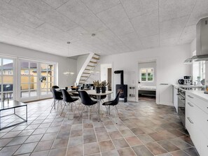 A spacious kitchen with a dining area, a built-in stove, and a large window. - 4 Star Holiday Home in Lokken (Lokken)
