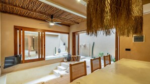 Una habitación amplia con una gran mesa de comedor, un ventilador de techo y vistas a una escalera que conduce a un balcón.