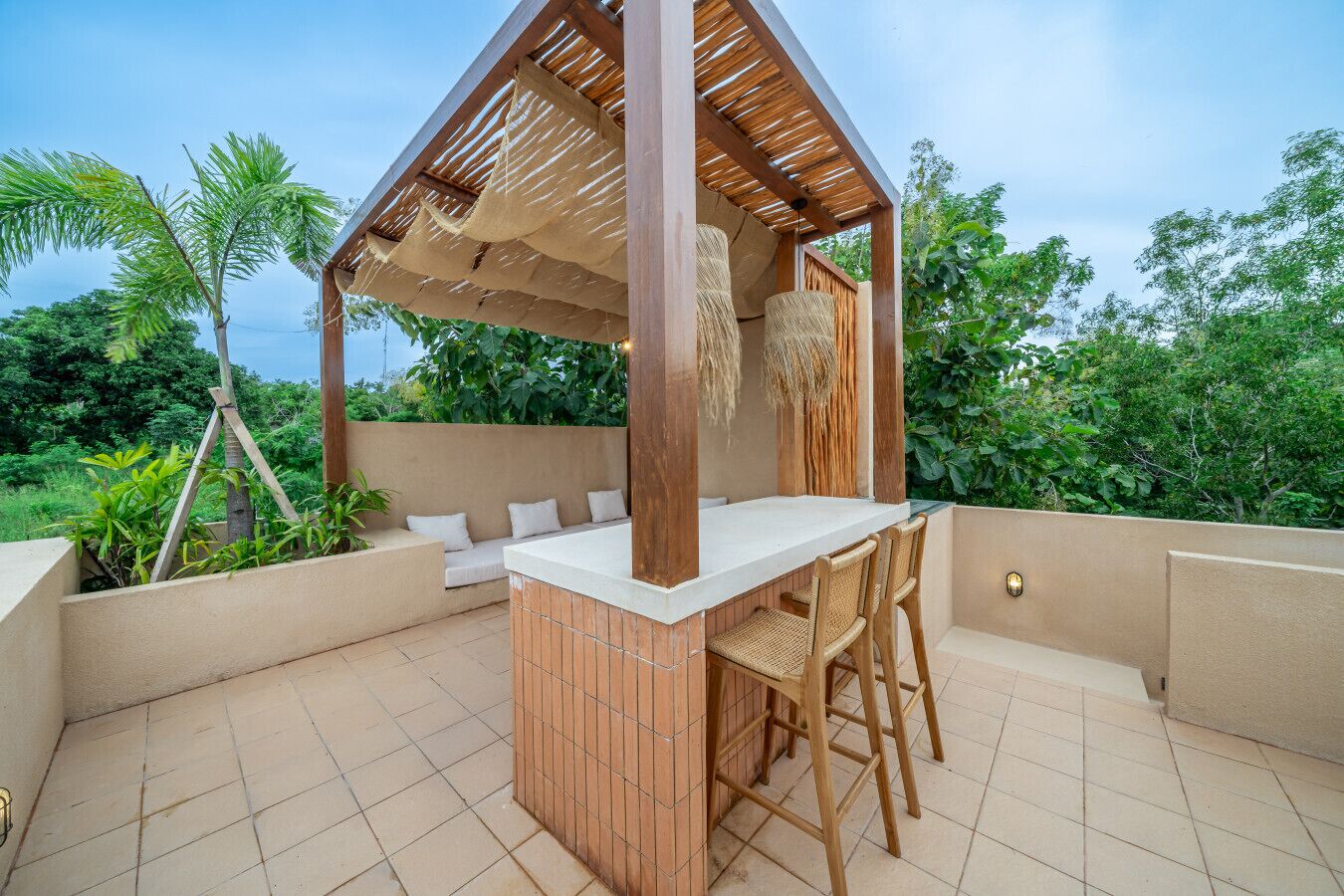 An outdoor patio with a wooden pergola, a white countertop, and seating.