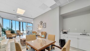 Un'area pranzo moderna con sedie in vimini, un tavolo con piano in vetro e vista sull'esterno.