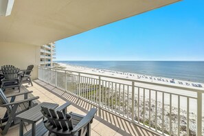 Un balcon avec des sièges pour l’extérieur et une vue sur la plage.