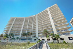 A multi-story hotel with a modern design, featuring balconies and a central walkway. - Admirals Quarters 708 | Beachfront Views | Luxury Amenities | Heart of Orange Beach (Orange Beach)