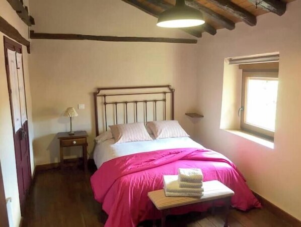 Une chambre à coucher avec un lit, une table de chevet, une fenêtre et une porte.