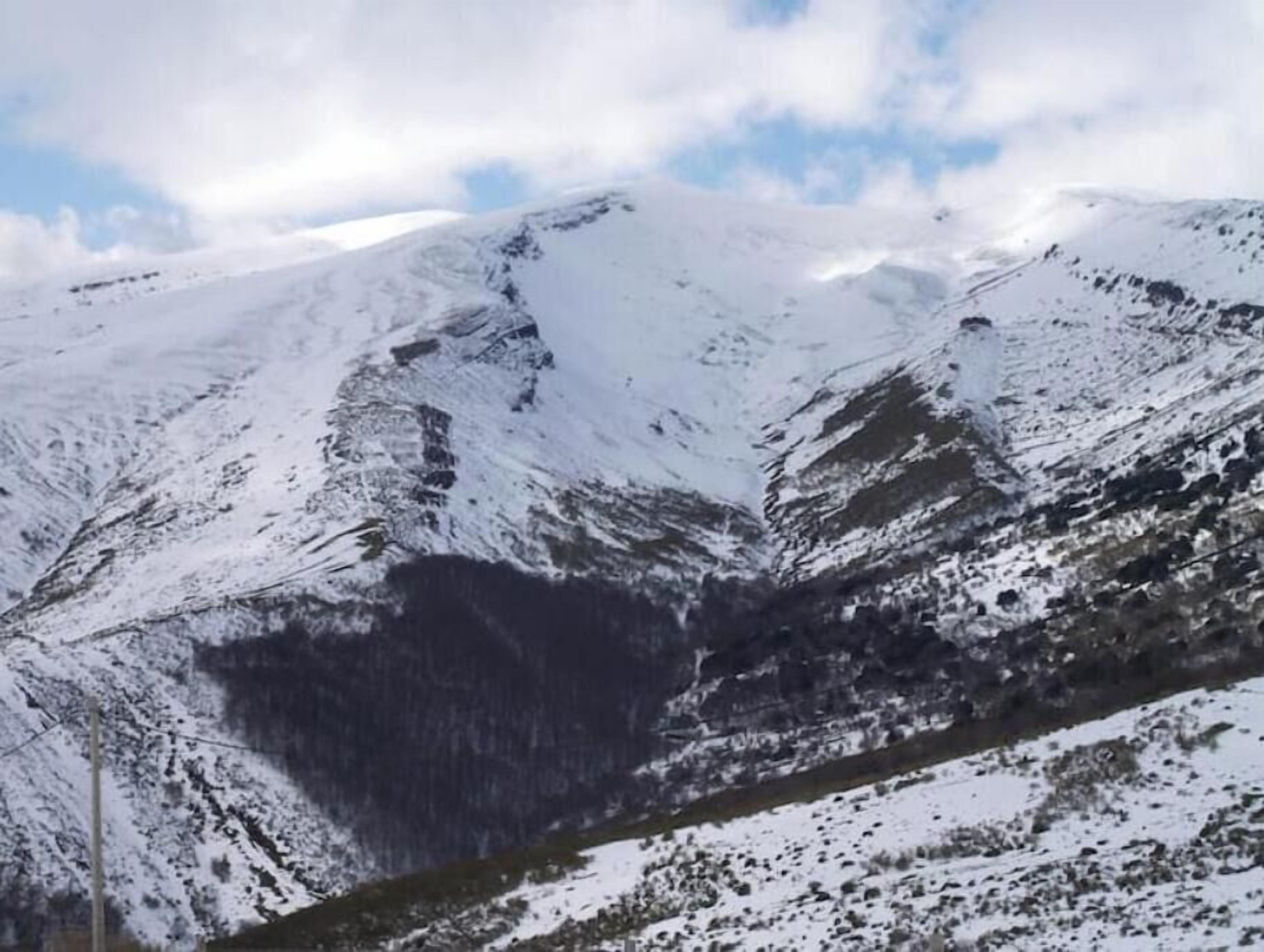 A mountainous landscape with snow-covered slopes and a clear sky.
