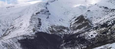 A mountainous landscape with snow-covered slopes and a clear sky.