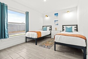 A bedroom with two beds, a window with curtains, a nightstand, and a rug. - Bright & Spacious 3BR | Close to Beaches (West Palm Beach)