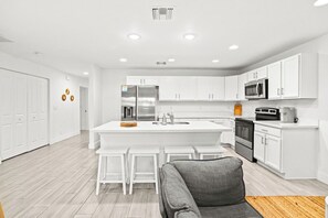 A modern kitchen with white cabinetry, a central island, and a built-in oven. - Bright & Spacious 3BR | Close to Beaches (West Palm Beach)