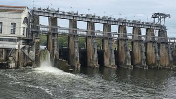 A dam with water flowing over it, a bridge, and a building with a staircase.