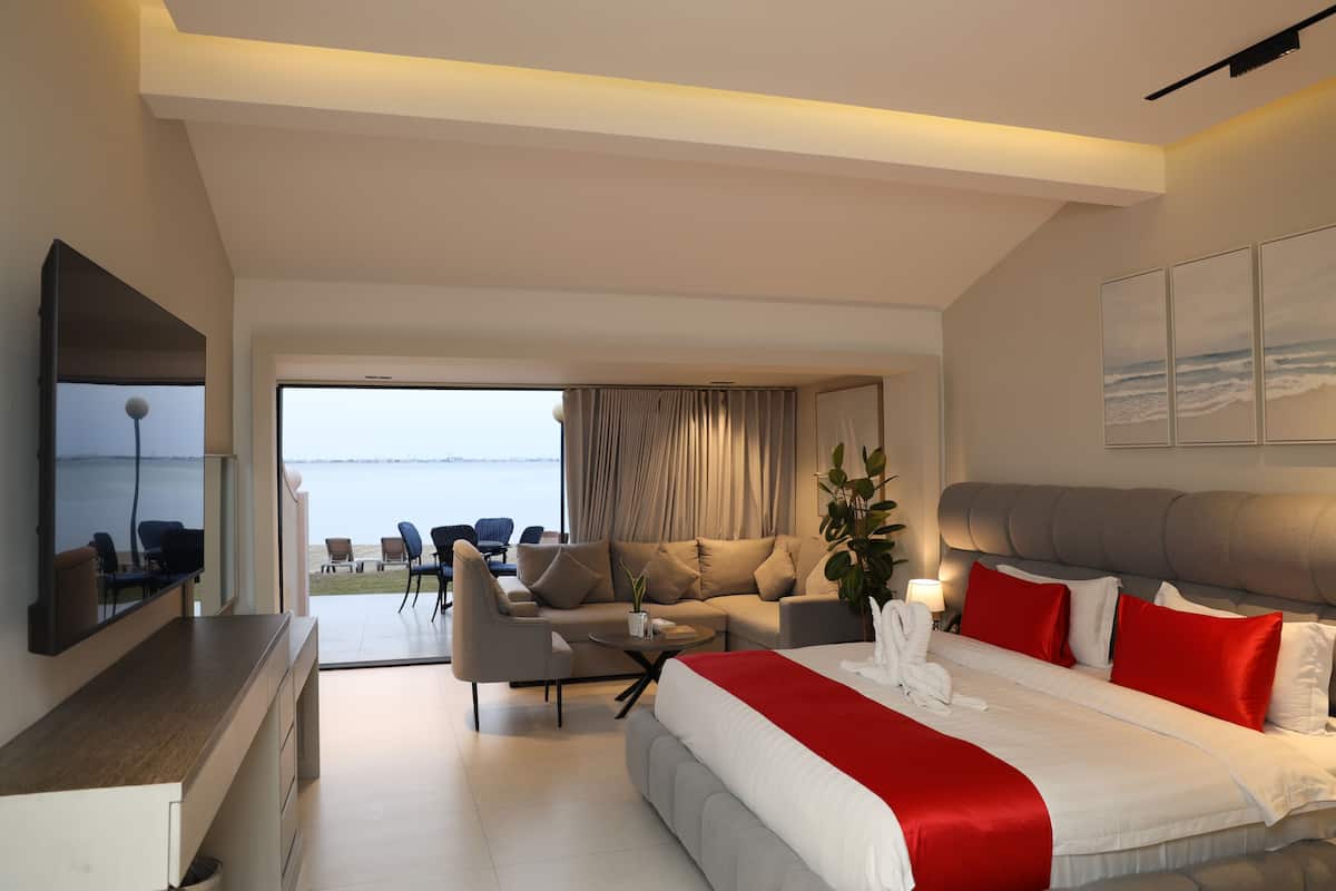 Una habitación de hotel moderna con una cama grande, un sofá, una mesa de comedor y un televisor.