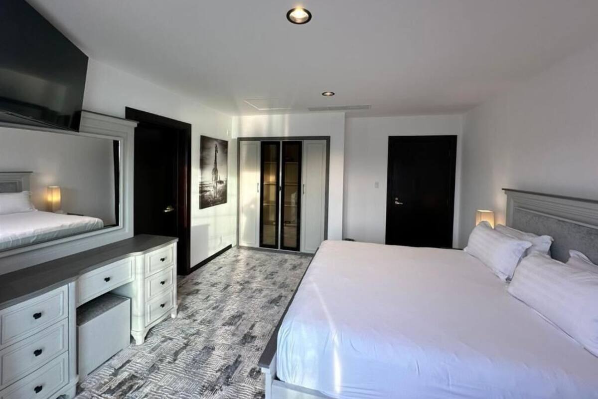 Una habitación de hotel con cama, cómoda, armario y puerta.