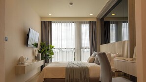 Ein modernes Hotelzimmer mit Bett, Nachttisch, Fernseher und Schreibtisch mit Stuhl.