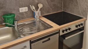 A kitchen with a dishwasher, stove, and a sink.