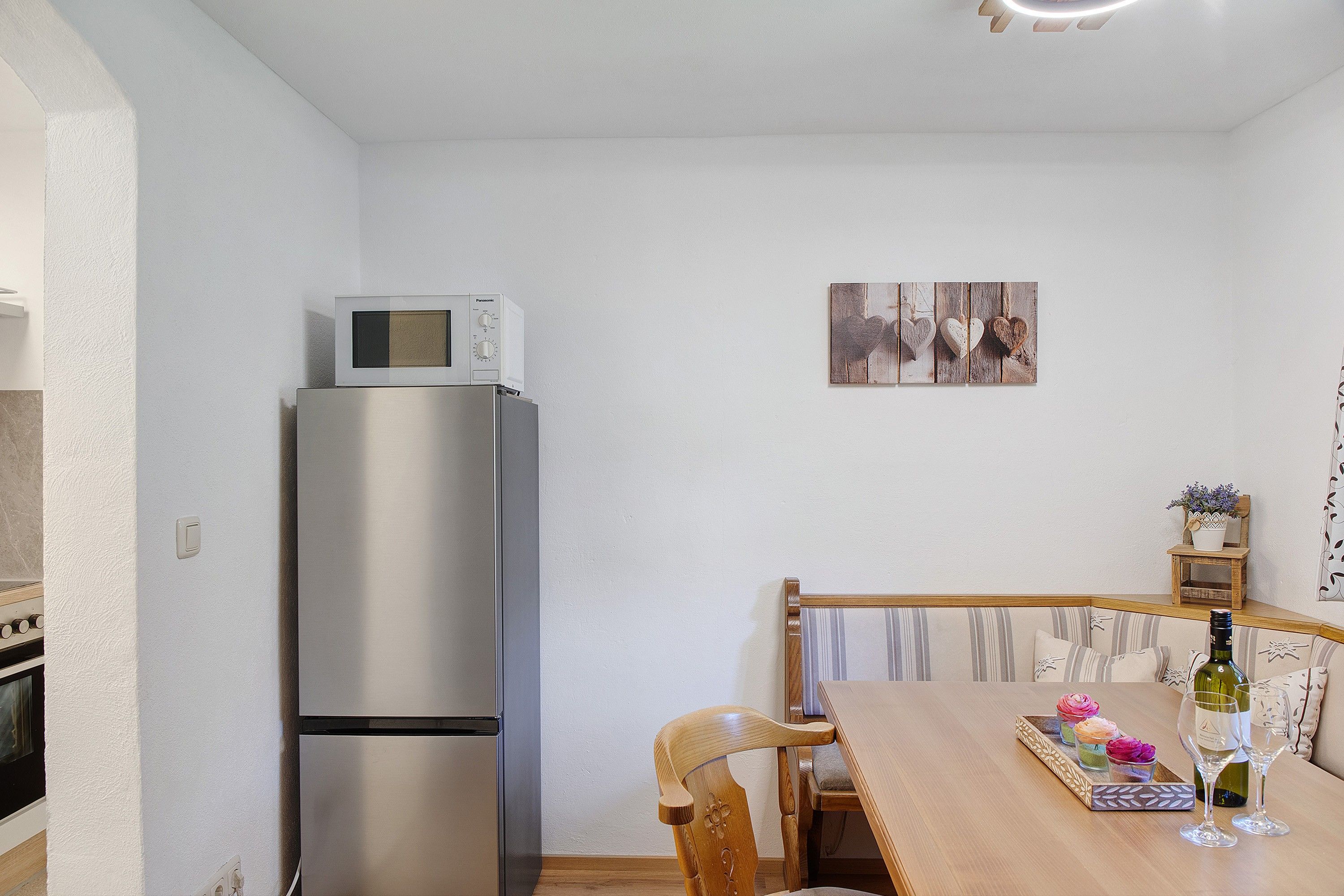 Eine Küche mit einem Edelstahl-Kühlschrank, einer Mikrowelle und einem Esstisch mit Stühlen.