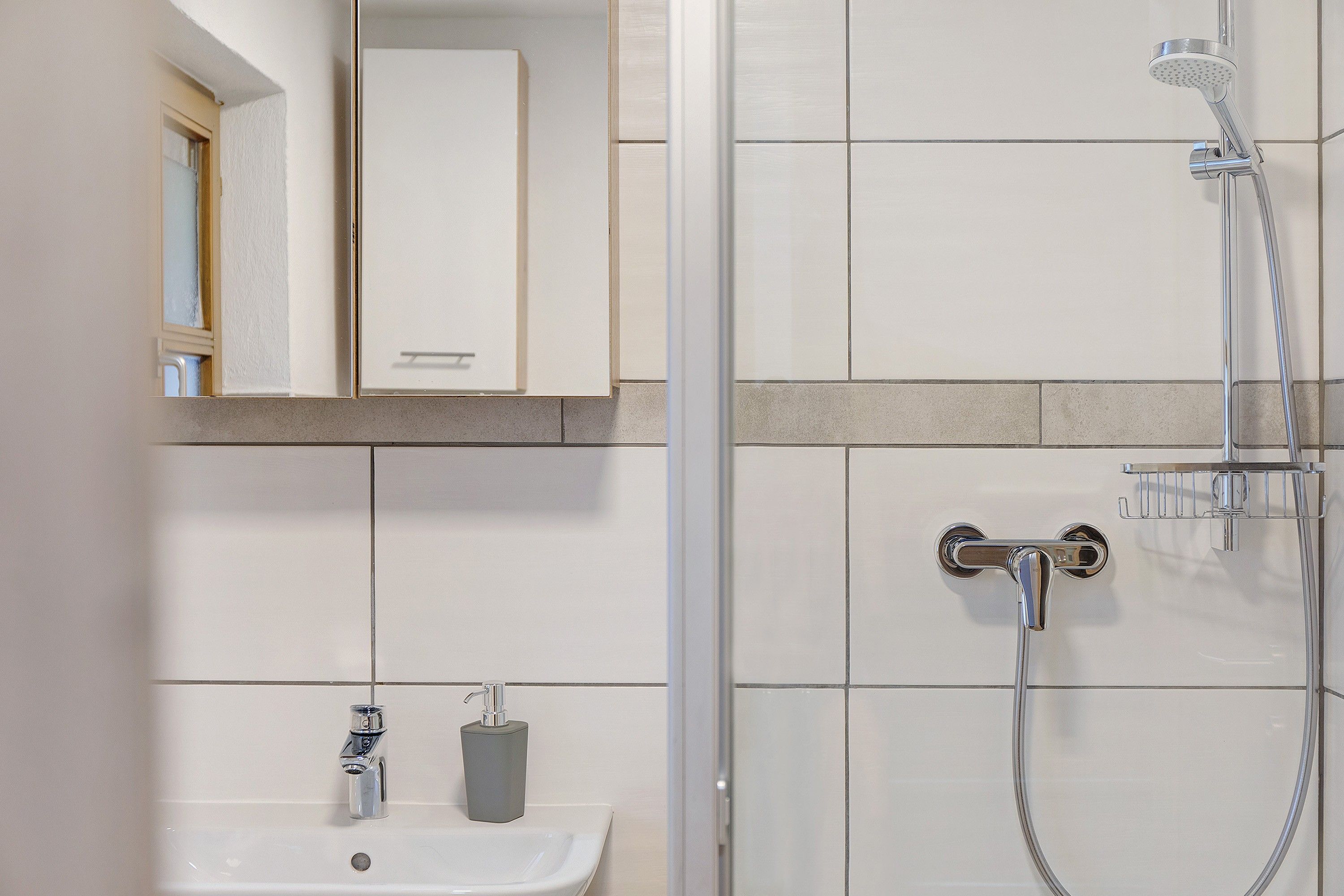 Ein Badezimmer mit Dusche, Waschbecken und Spiegel.