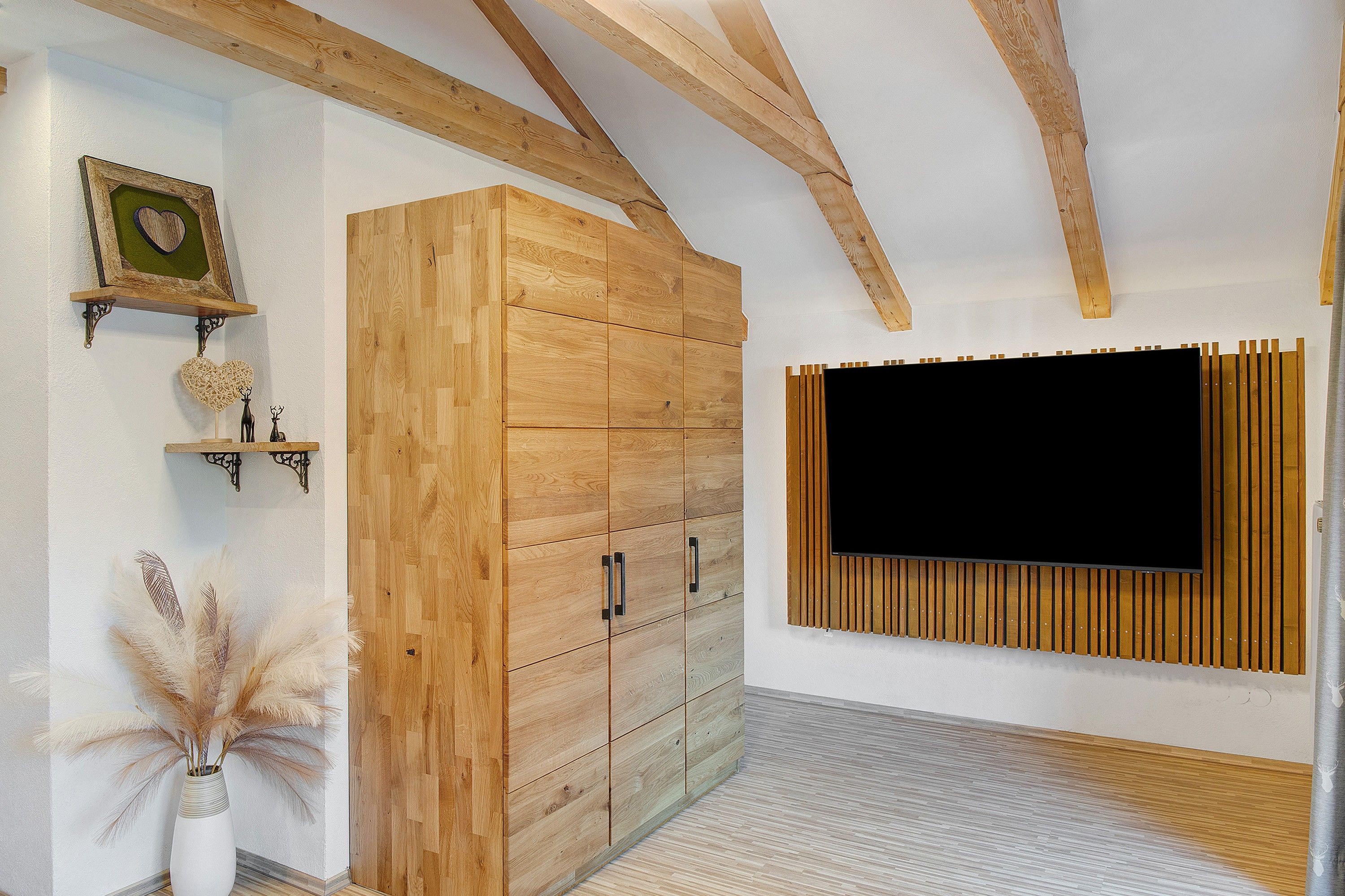 Ein Zimmer mit einem Holzschrank, einem Wand-Fernseher und Dekoration an der Wand.