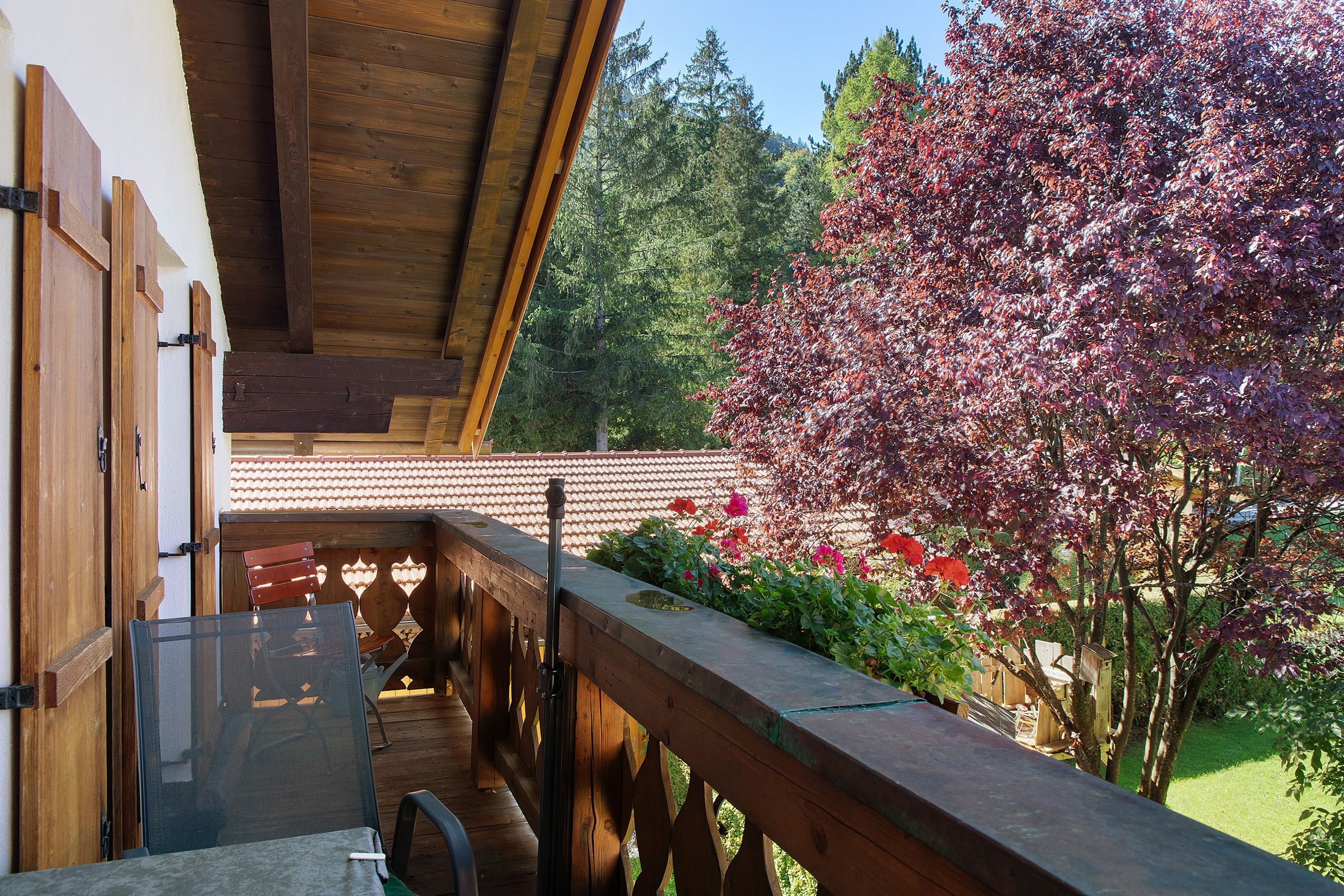 Ein hölzerner Balkon mit Blick auf einen Garten und Bäume.