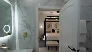 Ein Badezimmer mit Marmorwand, Waschbecken und einem Spiegel mit Beleuchtung.