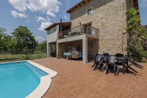 A stone building with a pool and outdoor seating.