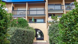 Un edificio residencial de varios pisos con balcones, un arco central y abundante vegetación.