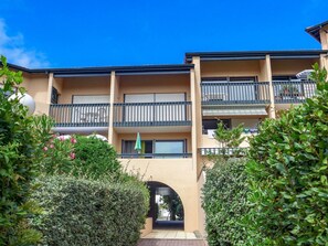 A multi-story residential building with balconies, a central archway, and surrounding greenery. - Cozy apartment 2 min walk to beach - 4 guests (Anglet)