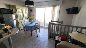 Una cocina equipada con microondas, refrigerador y una mesa de comedor con sillas.